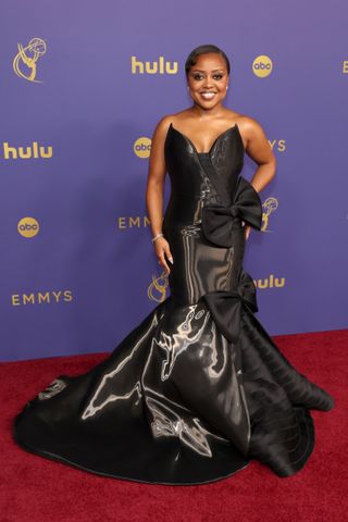 Quinta Brunson wears a black strapless gown with bows on it.