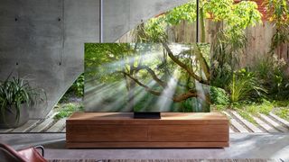 Samsung QLED TV in a brightly lit room with trees in the background and on screen