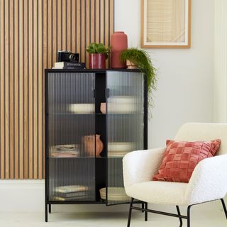Living room with wood panelling with boucle armchair and black storage cabinet