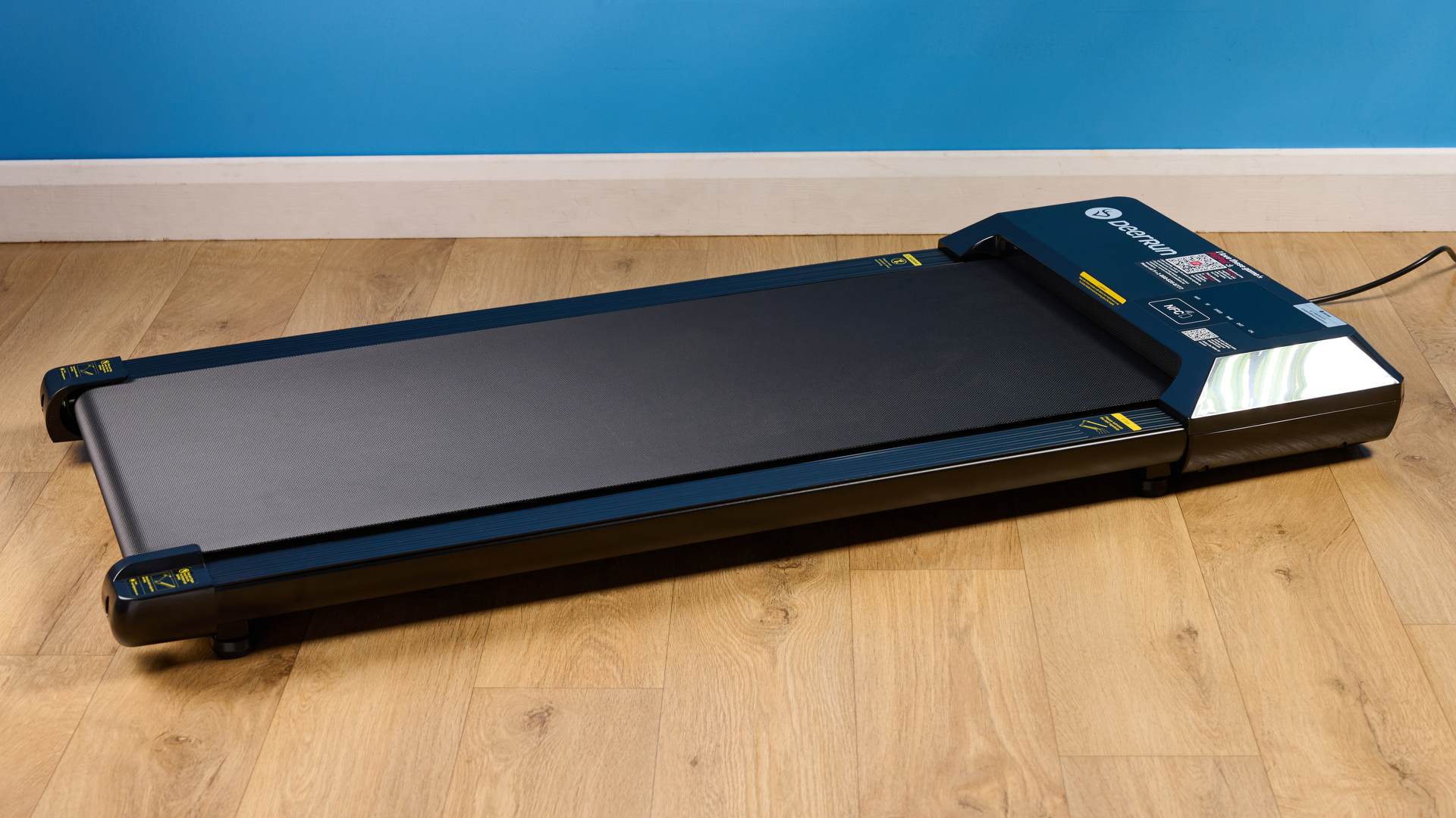 the deerrun q1 mini under desk treadmill walking treadmill in a home office with a blue wall and wooden floor
