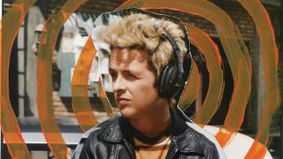 A man with big blonde hair and a leather jacket wearing the Marshall Monitor III ANC headphones with orange circles radiating from his head.