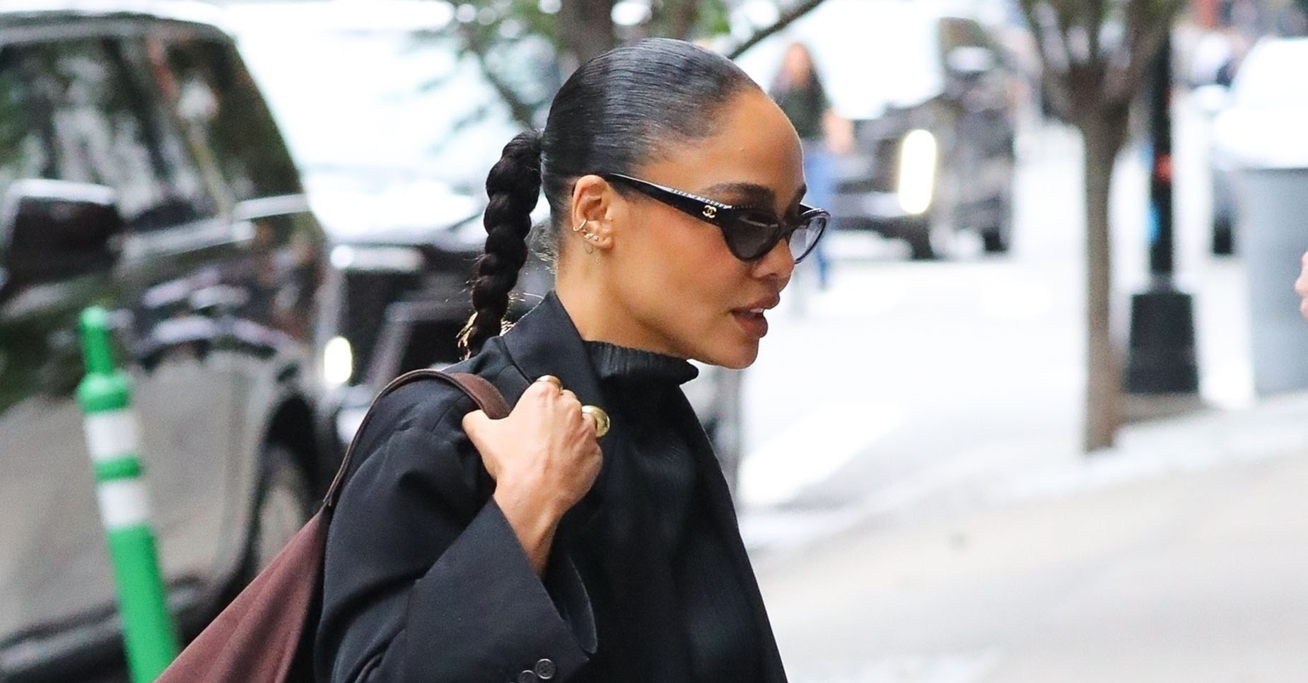 Tessa Thompson wearing a black coat, a plisse top and skirt, brown loafers