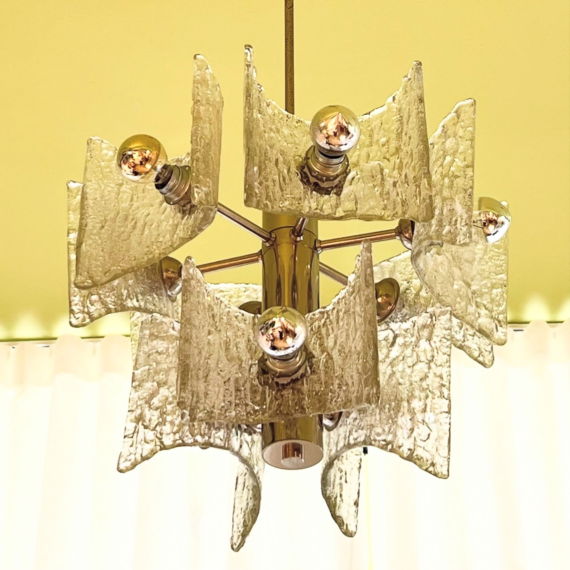 Murano glass and chrome chandelier against yellow wall