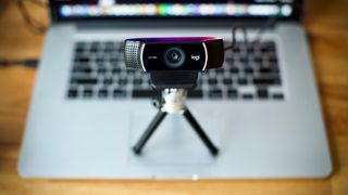 Une webcam Logitech sur un petit trépied, reposant sur un Macbook