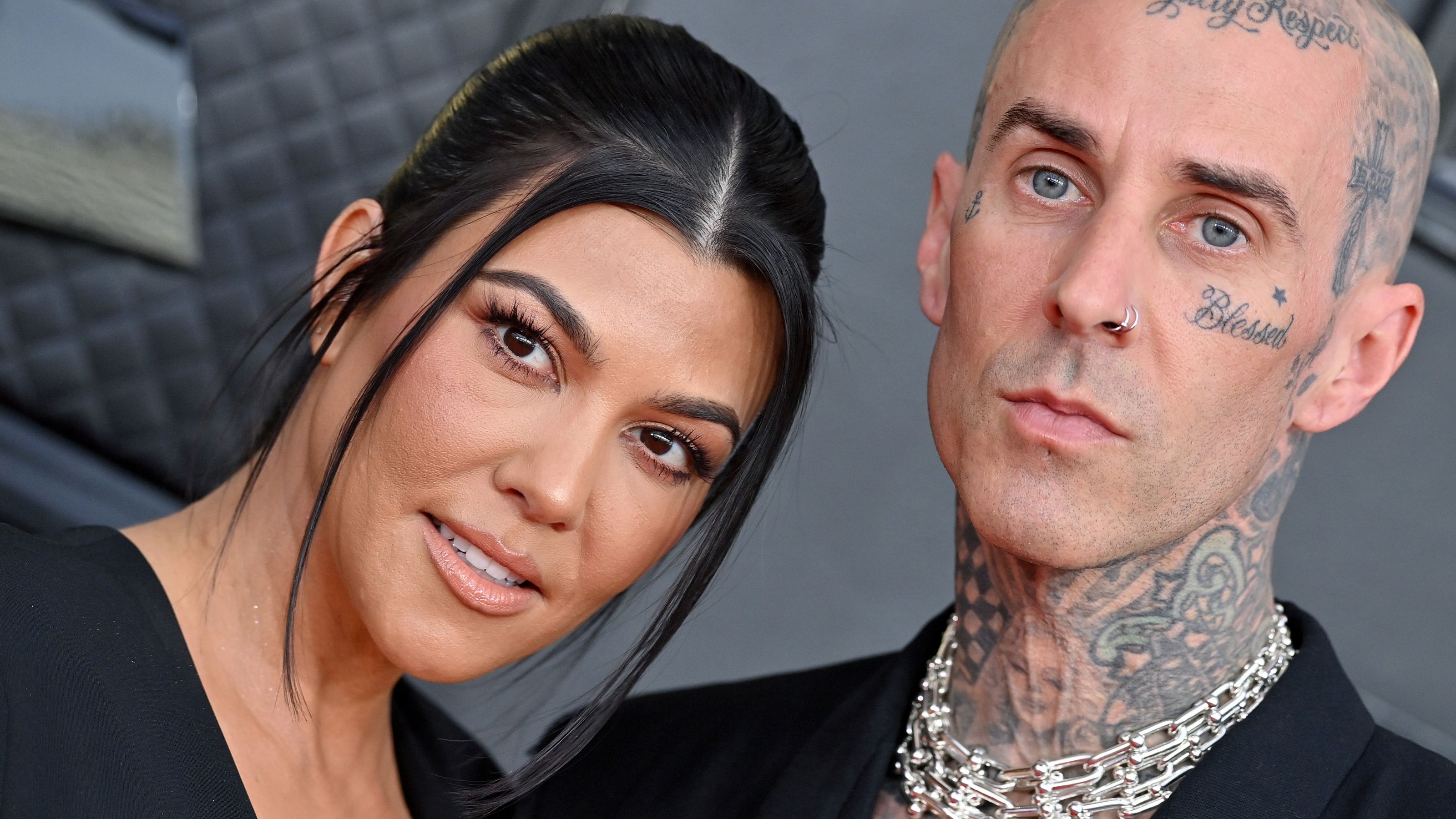 travis barker and kourtney kardashian on a gray background