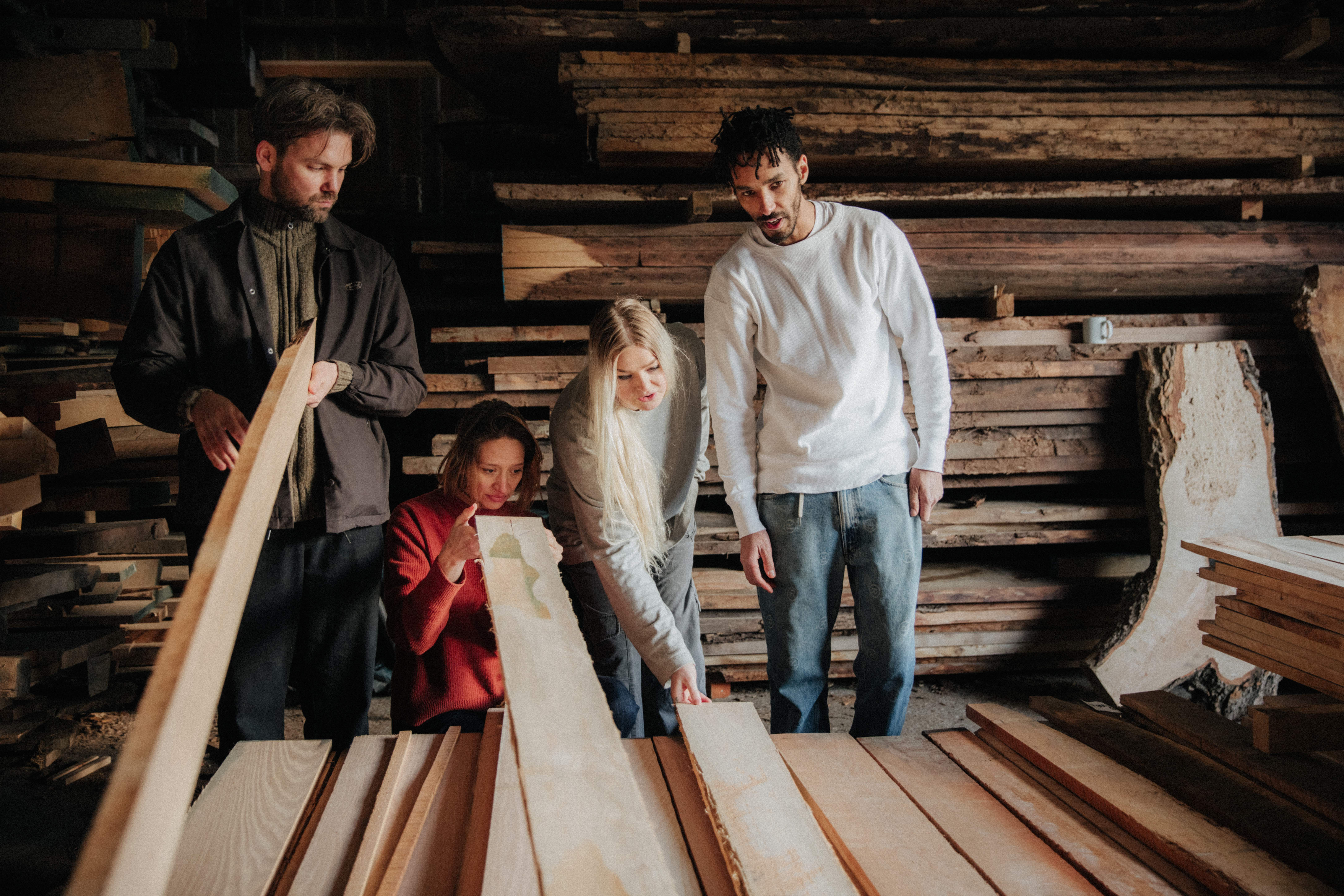 four designers inspect wooden planks in a workshop