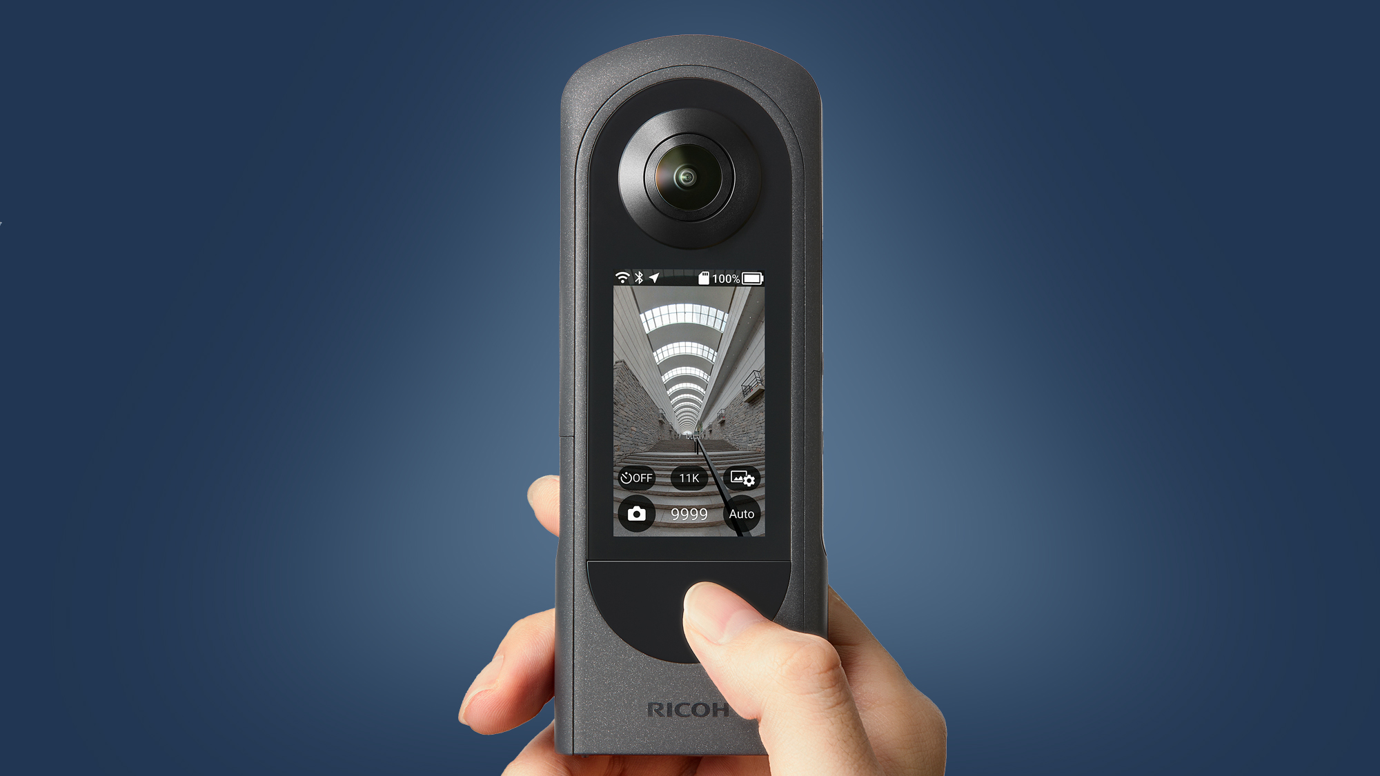 A hand holding the Ricoh Theta X 360 camera