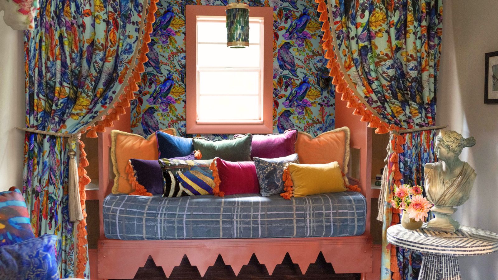 Nook with rounded seat, colorful pinned back curtains, wallpaper and pillows in jewel tones