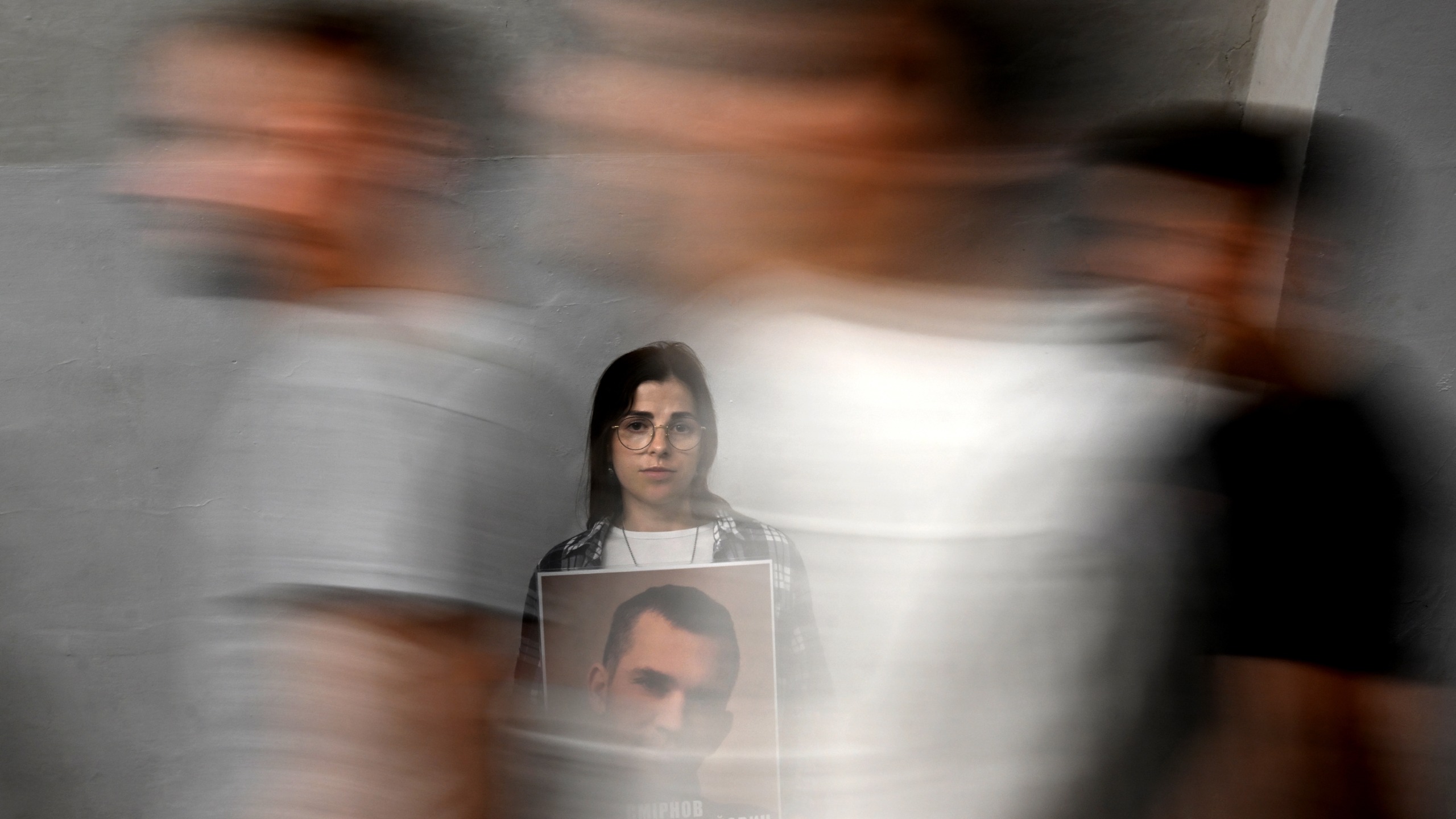 Commuters walk past a woman holding a placard depicting her boyfriend bearing the slogan "I dream of hugging the one I love" during a rally in support of Ukraine prisoners of war dubbed "Do not be silent! Captivity kills" held for security reasons in a metro station in Kyiv on September 20, 2026, amid the Russian invasion of Ukraine.