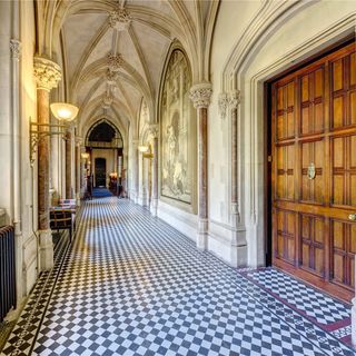 hallway with chequer board floor tiles and marble pillars lining