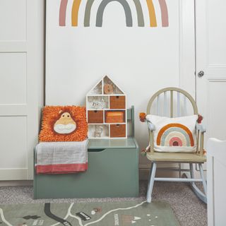 A playroom with a rocking chair and a toy box next to a play mat