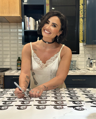 Demi Lovato in her kitchen with wallpaper above a tiled backsplash