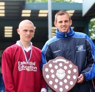 Kieran Trippier stands with a trophy and Woodhey High School PE teacher Lee Garcka