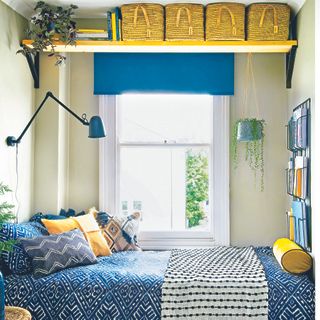 Yellow and blue bedroom with patterned bedding and a window next to the bed.