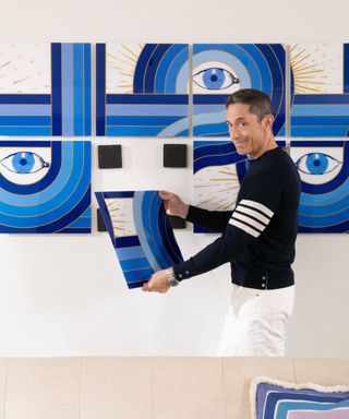 Jonathan Adler installing a piece of blue artwork