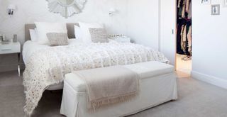 white bedroom with well made bed with throw and cushions to show a daily habit to keep a house clean and tidy