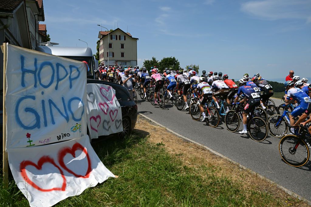 WEINFELDEN SWITZERLAND JUNE 17 A general view of the peloton competing close to a support detail in memory of Gino Mder during the 86th Tour de Suisse 2023 Stage 7 a 1835km stage from Tbach to Weinfelden UCIWT on June 17 2023 in Weinfelden Switzerland Photo by Dario BelingheriGetty Images