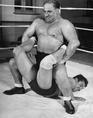 Black and white photo of Bert Assirati and Mike Marino wrestling in a ring.