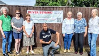 A photo of a residents group in front of a poster warning buyers