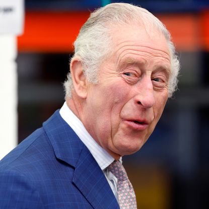 King Charles laughs while wearing a navy suit