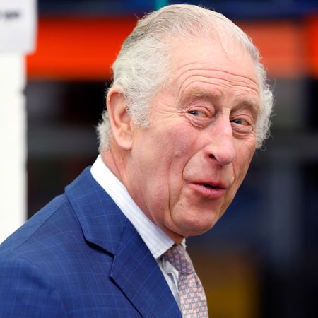 King Charles laughs while wearing a navy suit