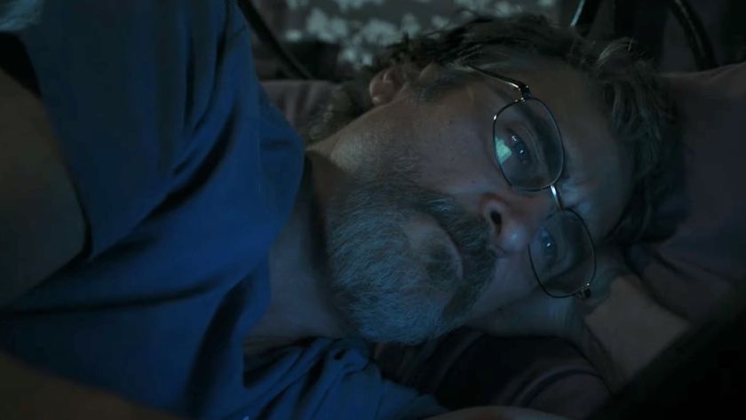 Joaquin Phoenix lying in bed looking at his phone in Eddington