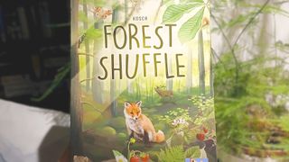 Forest Shuffle card game held up beside a plant