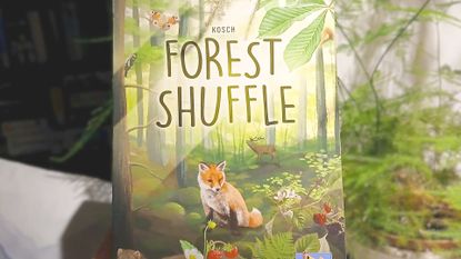 Forest Shuffle card game held up beside a plant