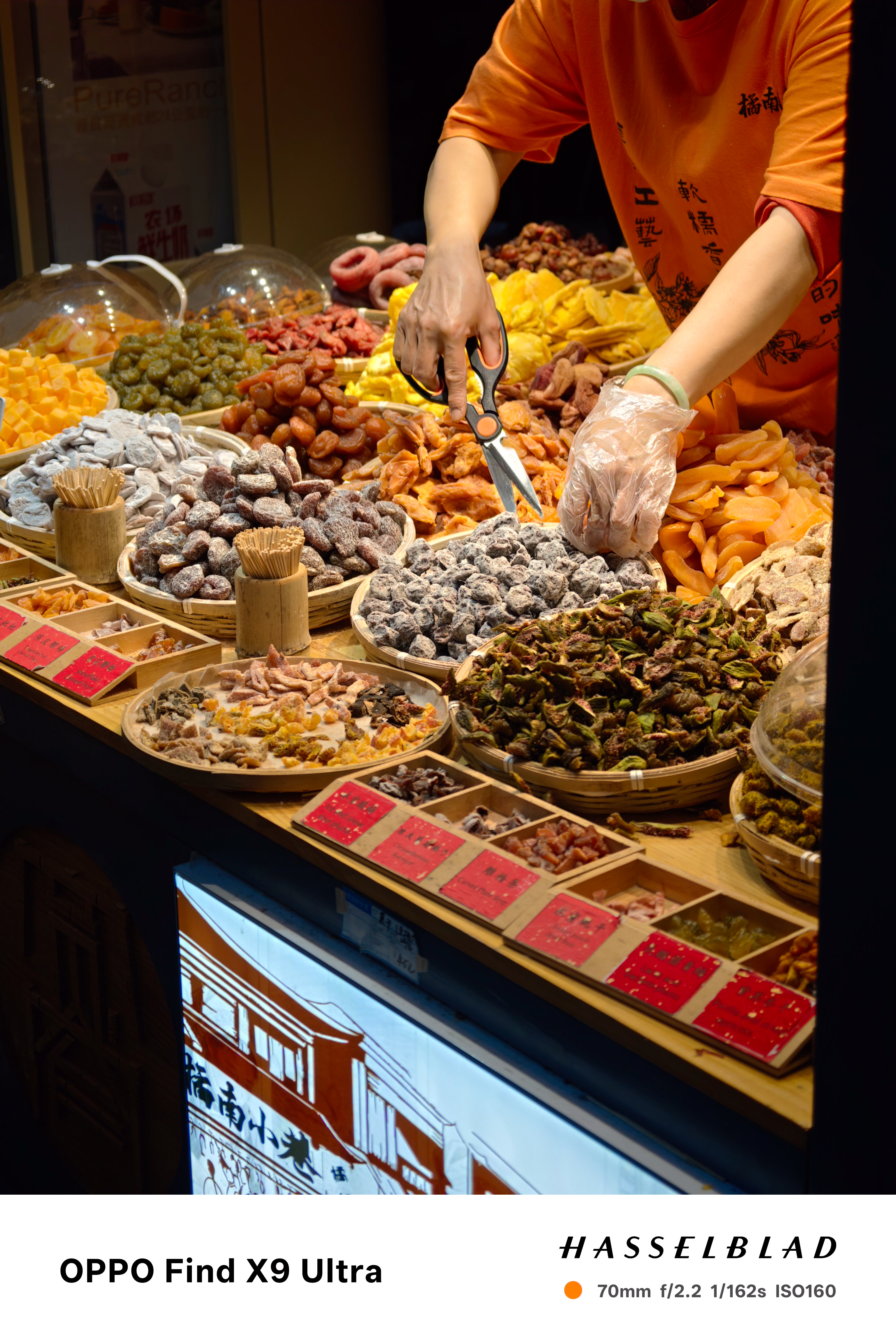 Vendor selecting dried fruit and preserved snacks at a market stall