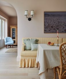 pastel room with a yellow skirted banquette seta and a pale pink walls