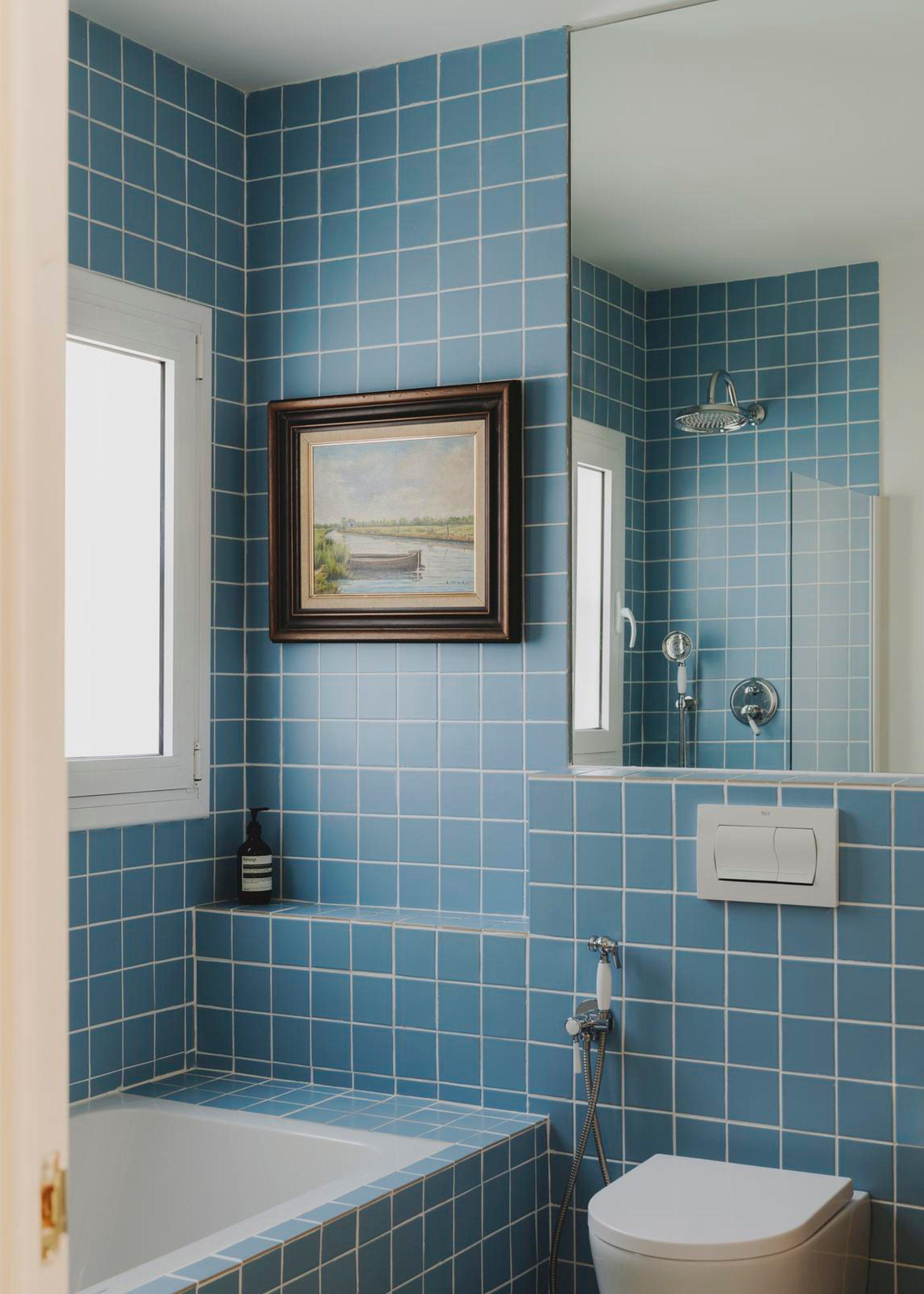 A bathroom with turquoise blue tiling and a bathtub
