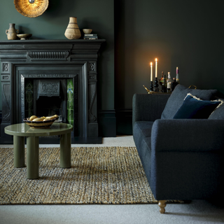 Green and grey rug on a grey carpet, dark blue sofa and green coffee table