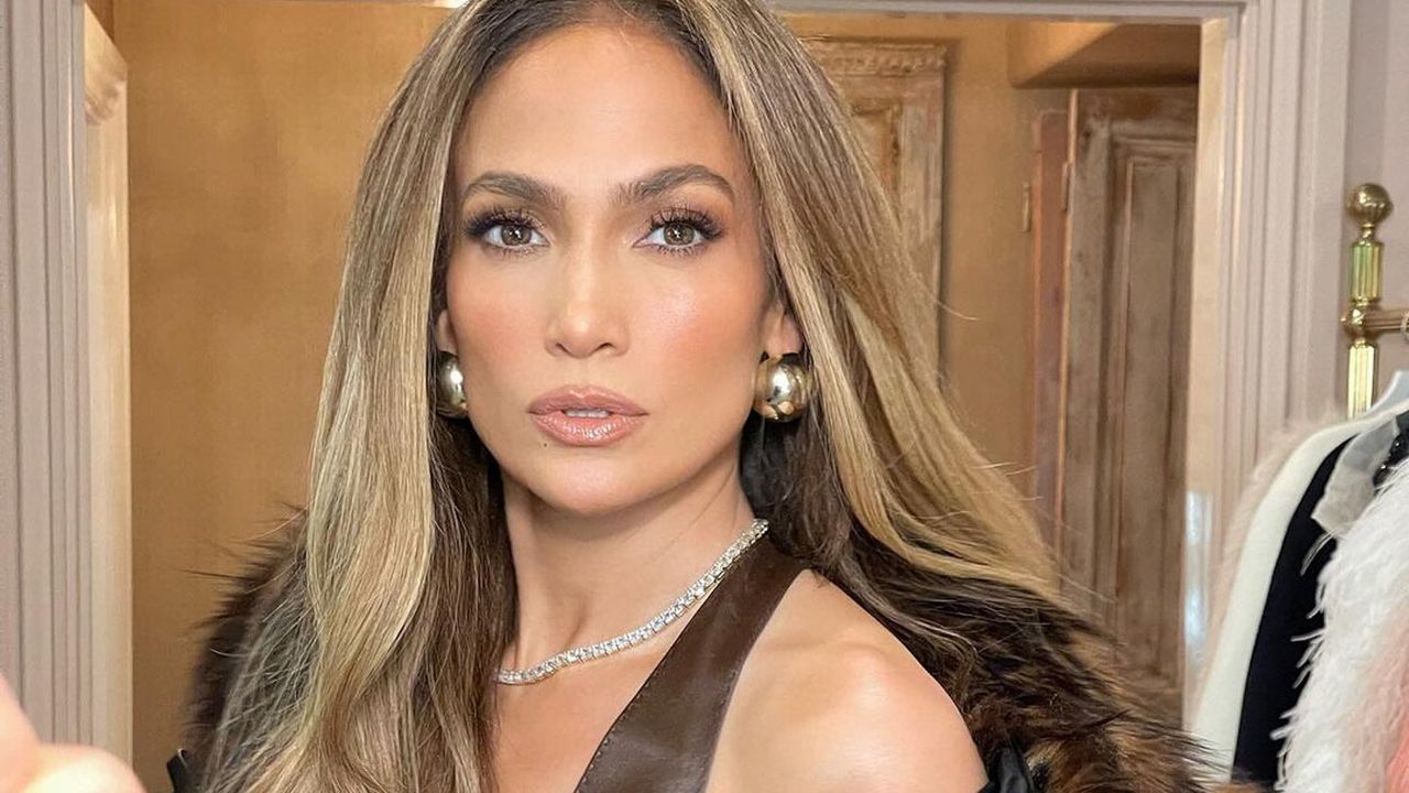 Jennifer Lopez wearing an all-brown outfit with a fur coat while posing in her closet