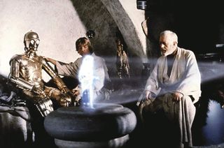 Screenshot from Star Wars with Obi-Wan Kenobi, Luke Skywalker and C3PO watching Princess Leia's hologram.