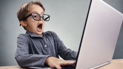 A child wearing glasses amazed at a laptop screen.