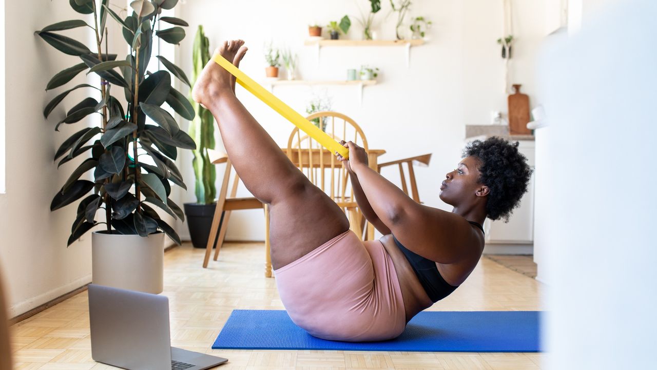 Woman doing boat pose with a long resistance band