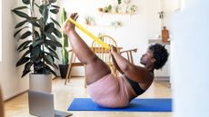 Woman doing boat pose with a long resistance band