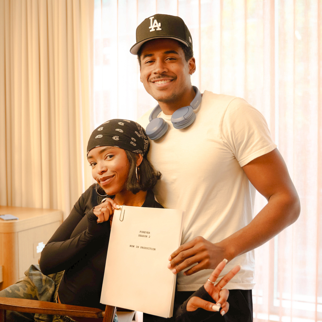 lovie simone and tk pose together smiling while getting ready backstage and holding up a script for forever season 2