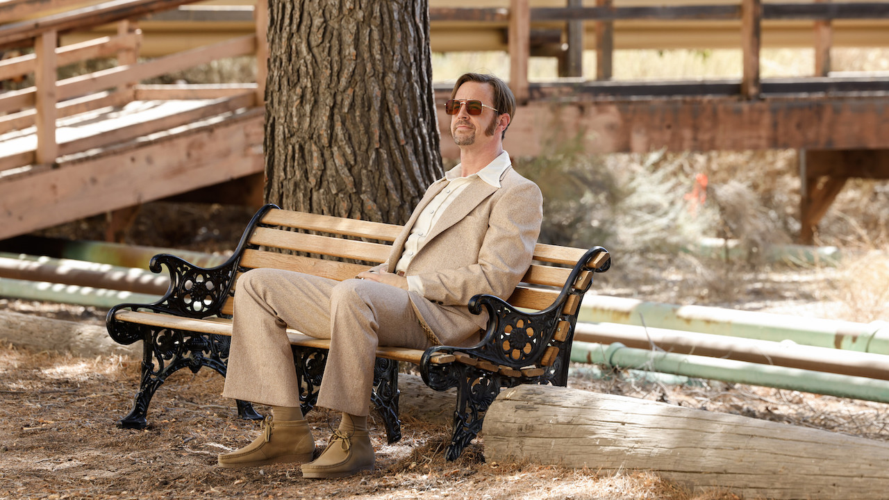 Sean Murray's Timothy McGee dressed in '70s attire and sitting on park bench in NCIS