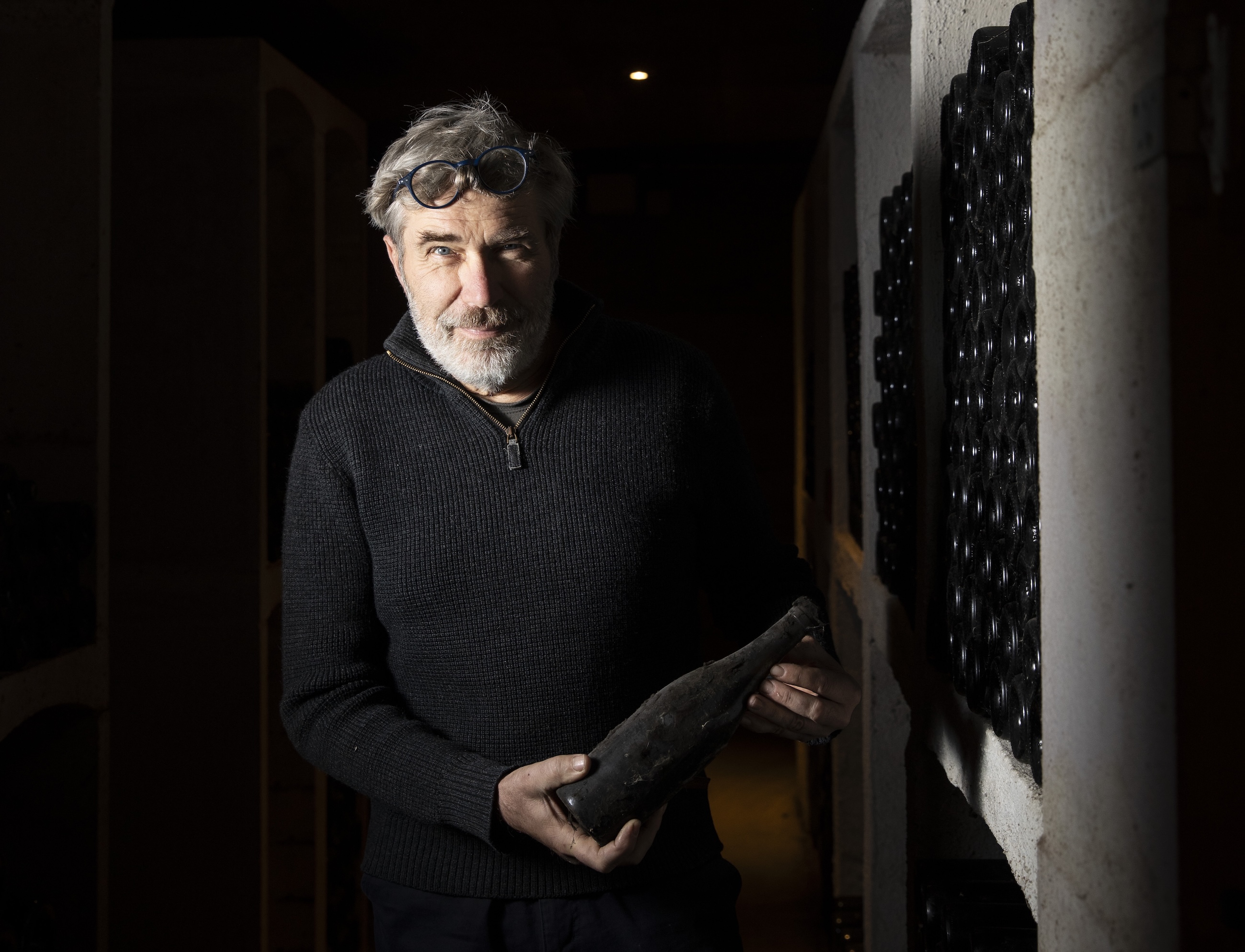 Trapet holding a bottle in his cellar