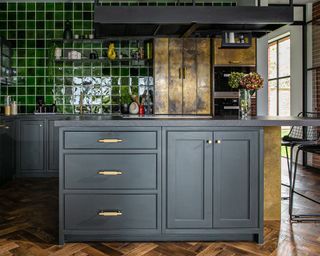 A Victorian industrial-style kitchen with black cabinetry and brass handles
