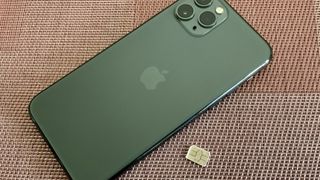 iPhone 11 in green next to a SIM card