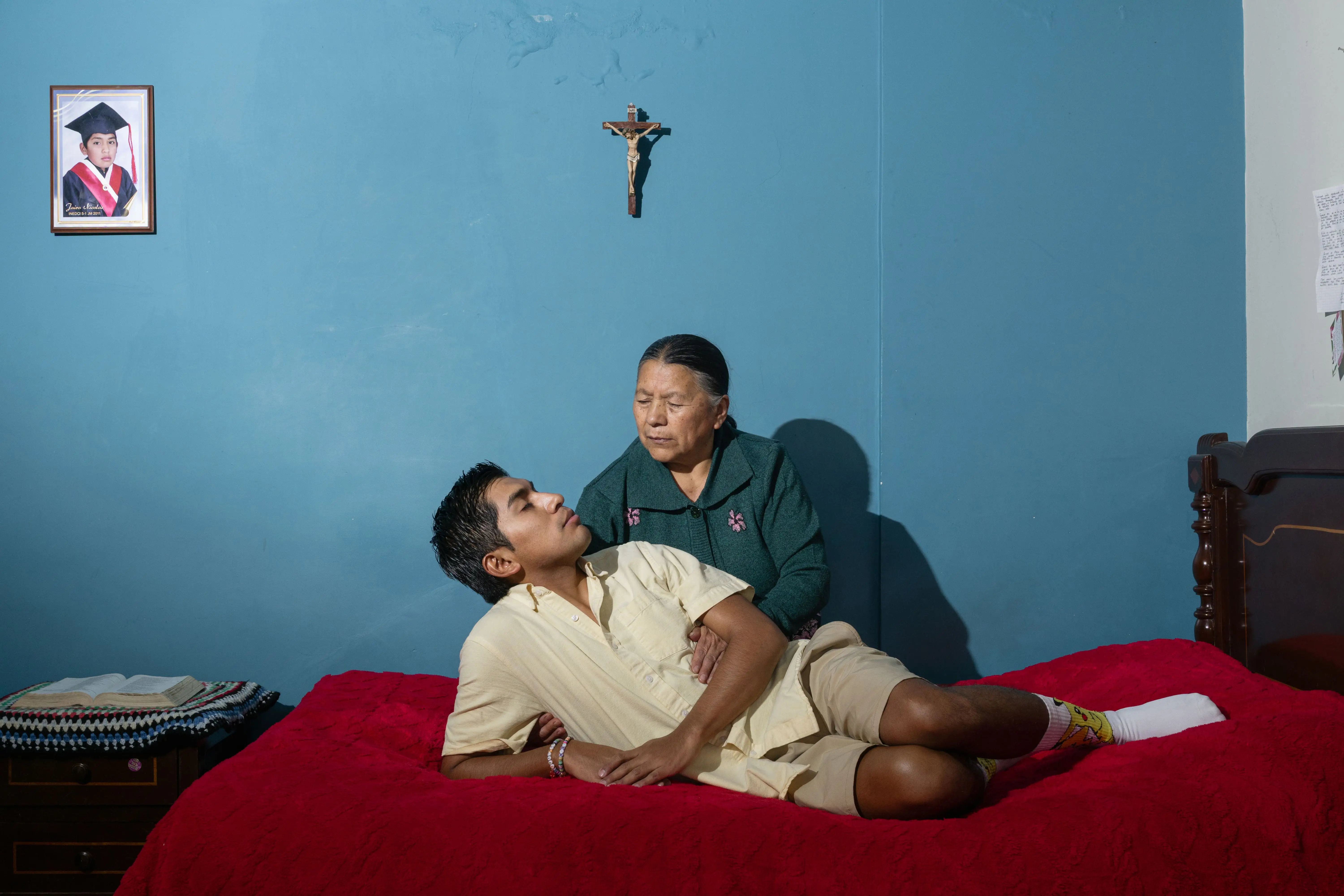 Mother embraces son on bed.