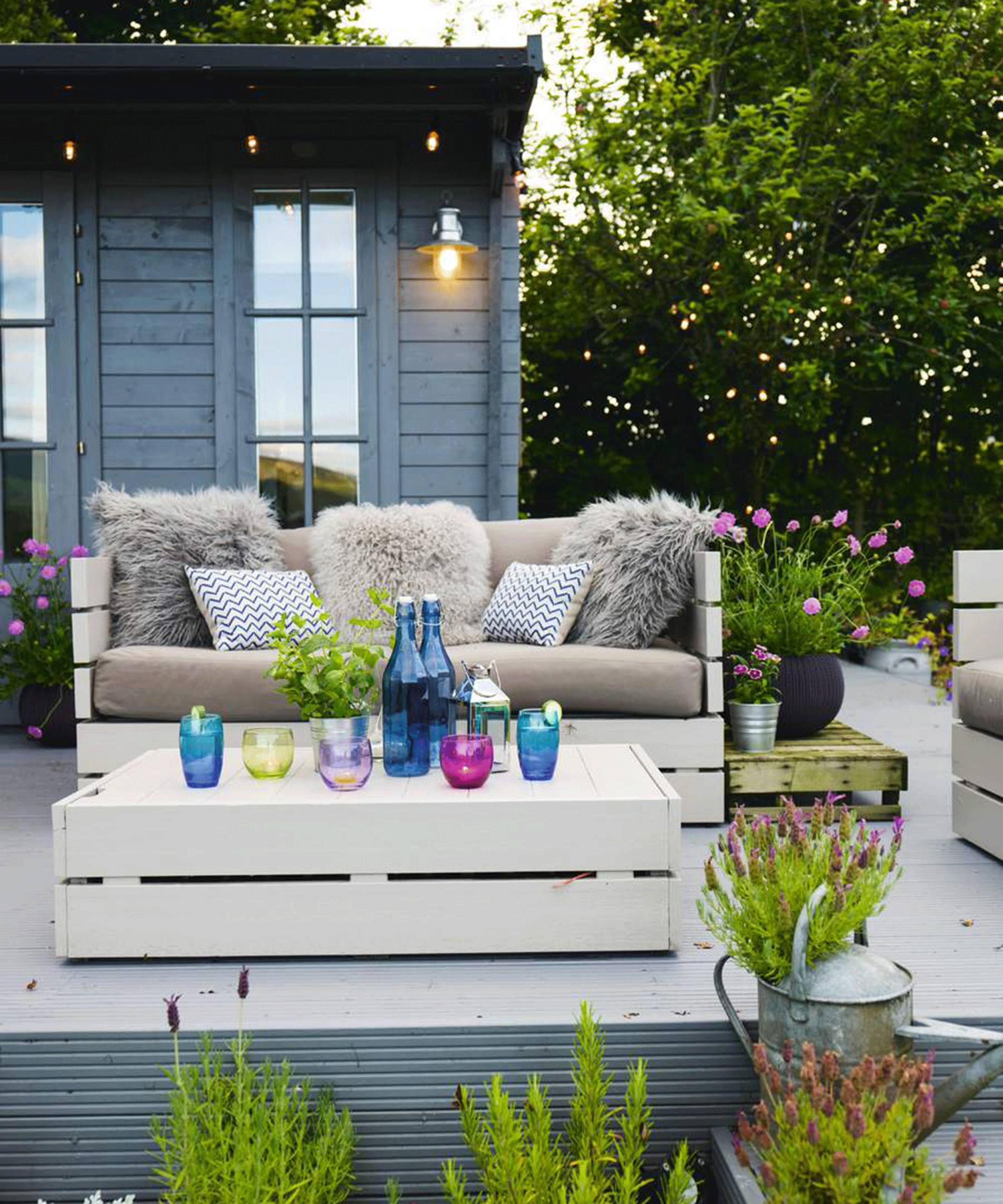 A backyard deck with blue garden room and cream painted pallet coffee table and outdoor sofa decor