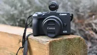 The Canon EOS M6 Mark II resting on a wooden beam in a garden