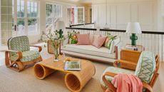 A white sitting room with green and pink accents and bamboo/rattan furniture