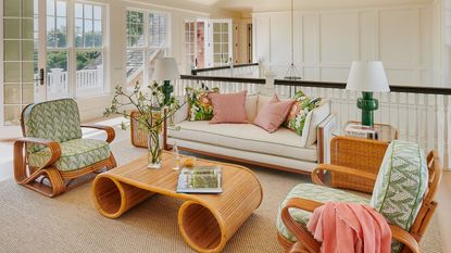 A white sitting room with green and pink accents and bamboo/rattan furniture