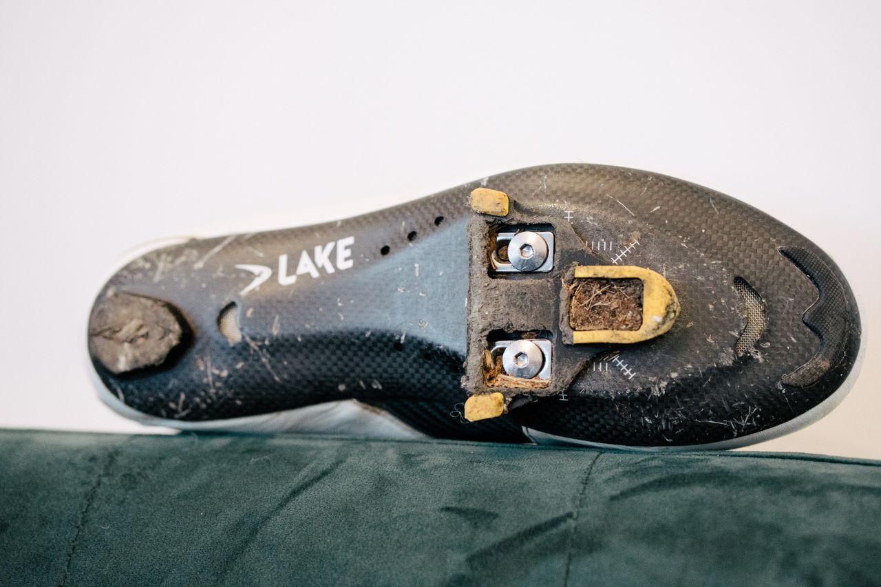 A white leather cycling shoe on a green sofa
