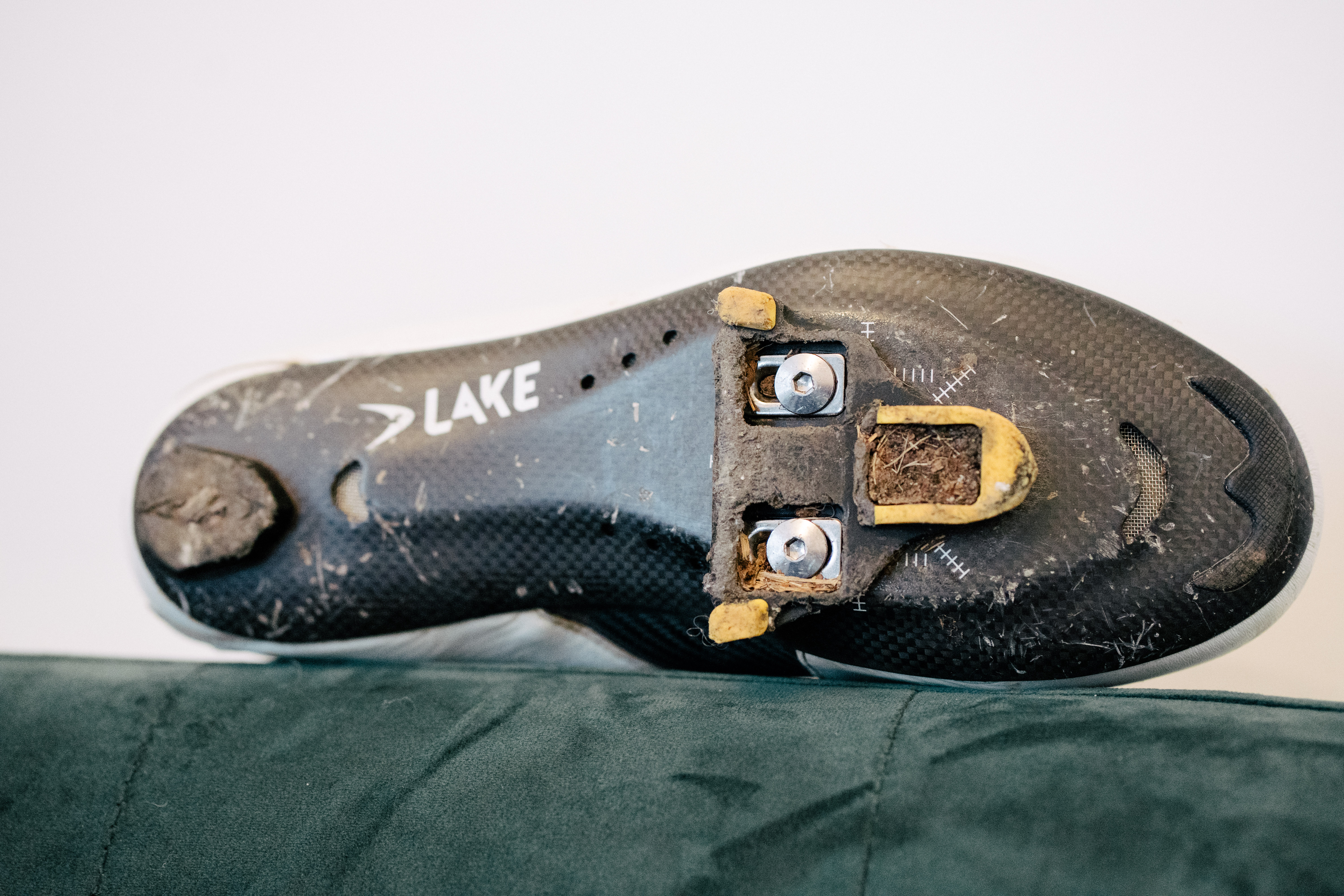 A white leather cycling shoe on a green sofa