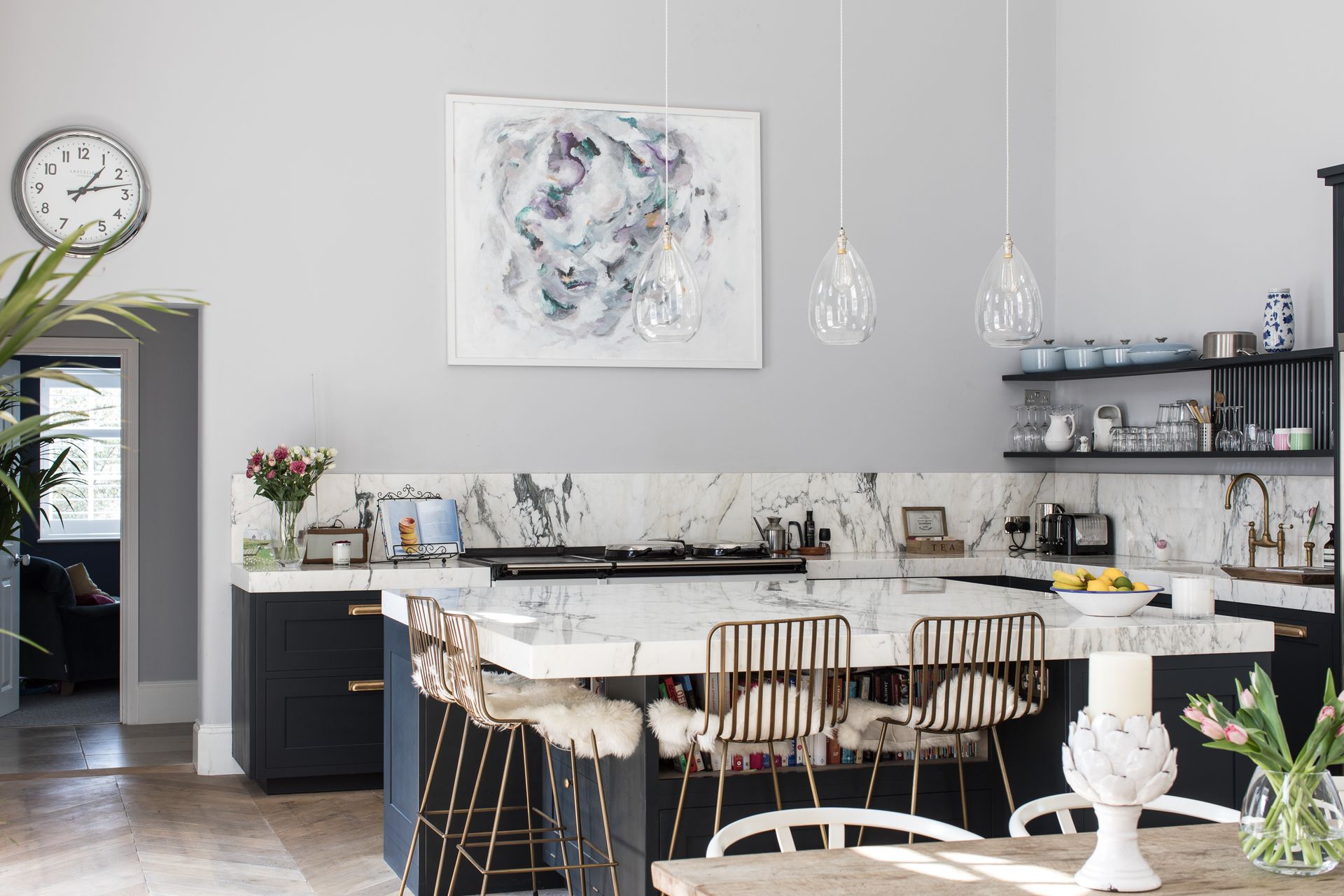 A pale gray kitchen with dark gray cabinetry and white marble countertops.